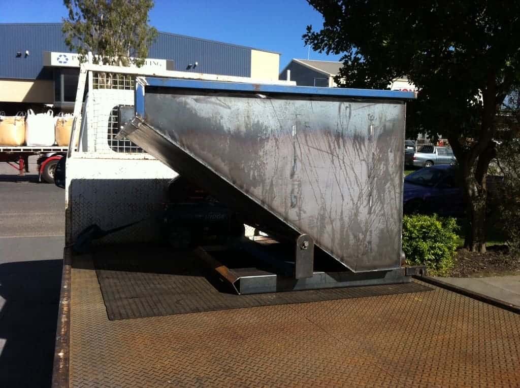 steel bin tipper attachment resting on the back of a delivery truck